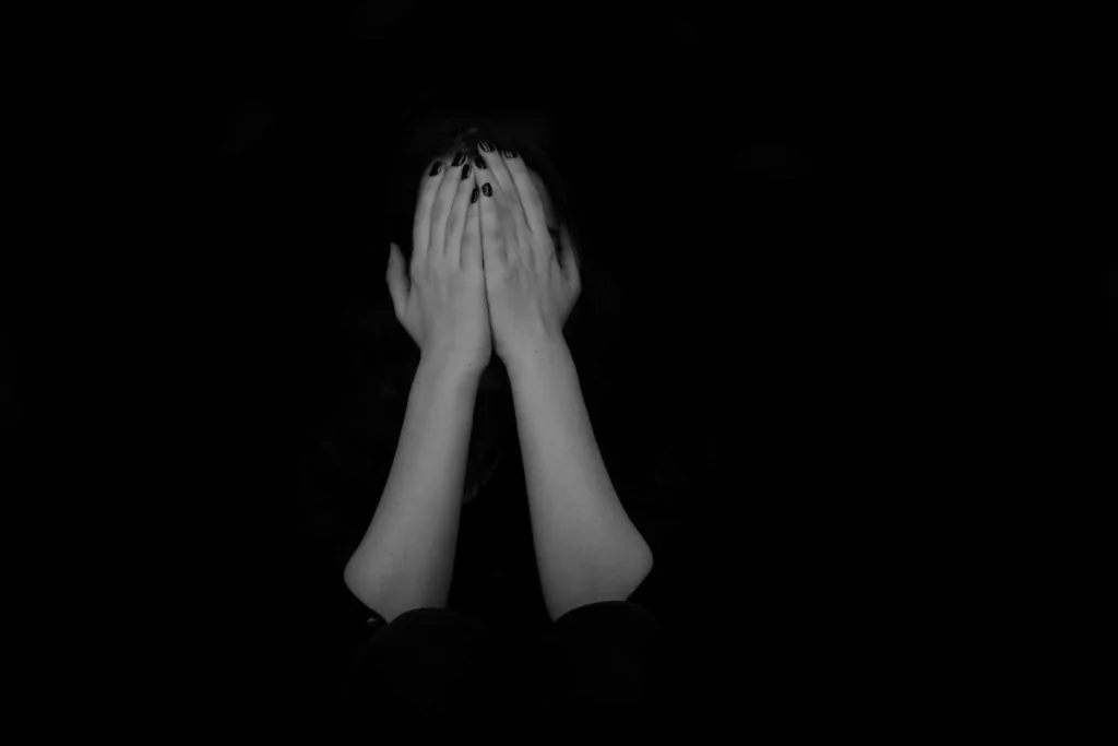 Sex abuse scaled A person hides in the dark with their face covered by their hands